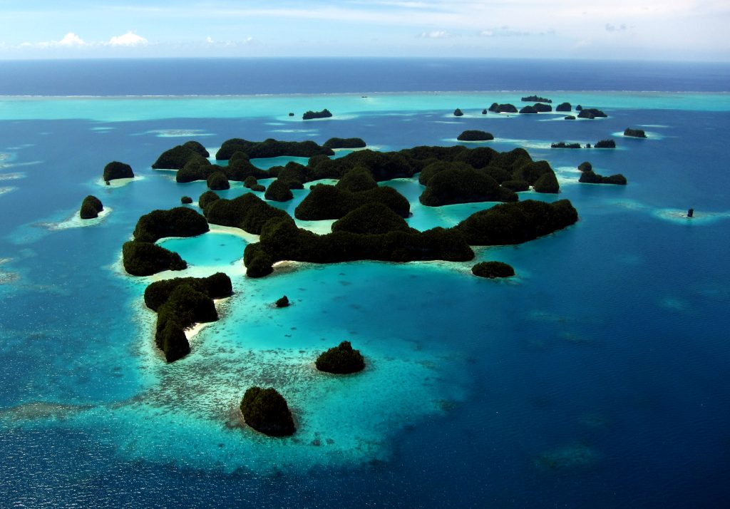 The Palauan Rock Islands adorned with lush greenery, white islets, and sections of shallow reefs.