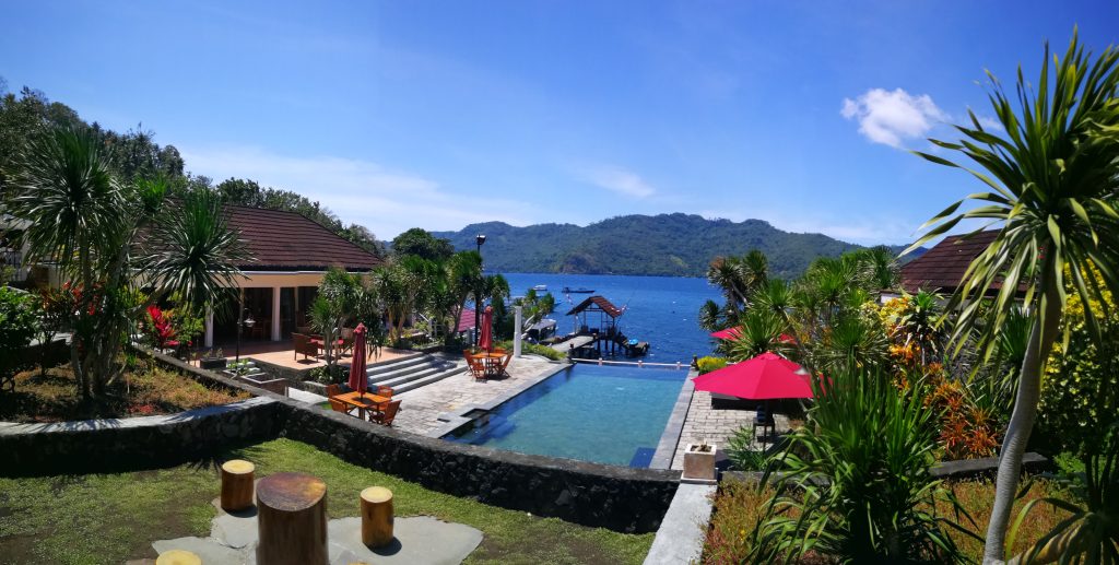 Villa at Solitude Lembeh Resort with infinity-edge pool, lush garden, and ocean view with a scenic island backdrop