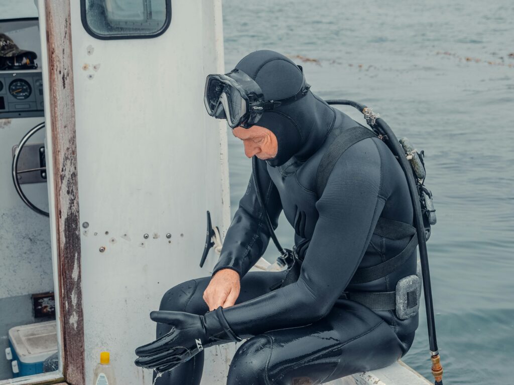 A man in a wetsuit sitting on a boat